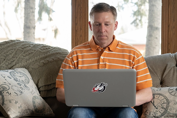 Student sitting on a couch with laptop on lap