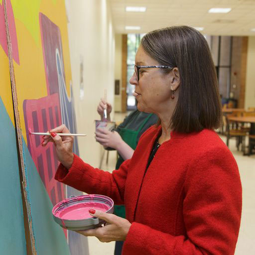 MSUM President Anne Blackhurst painting Church's United billboard